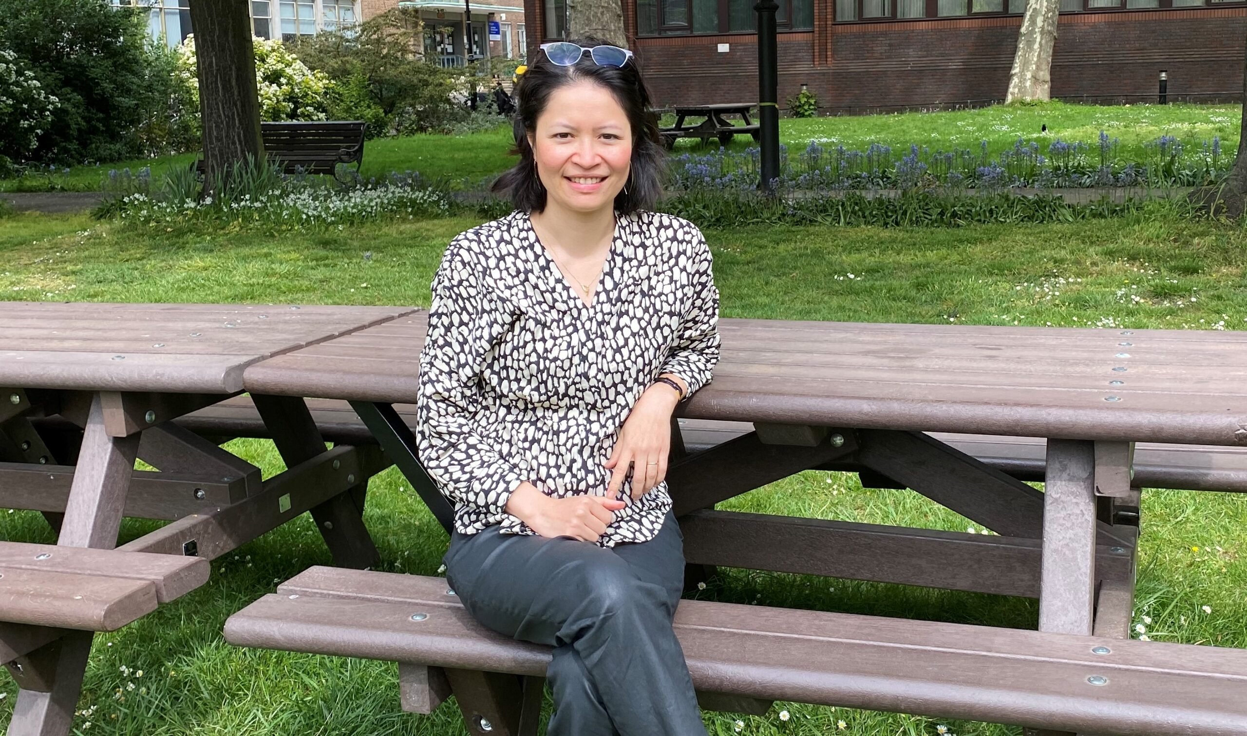 Dr Diu Nguyen sitting on a bench at Barts Cancer Institute, on Queen Mary University of London's Charterhouse Square Campus.