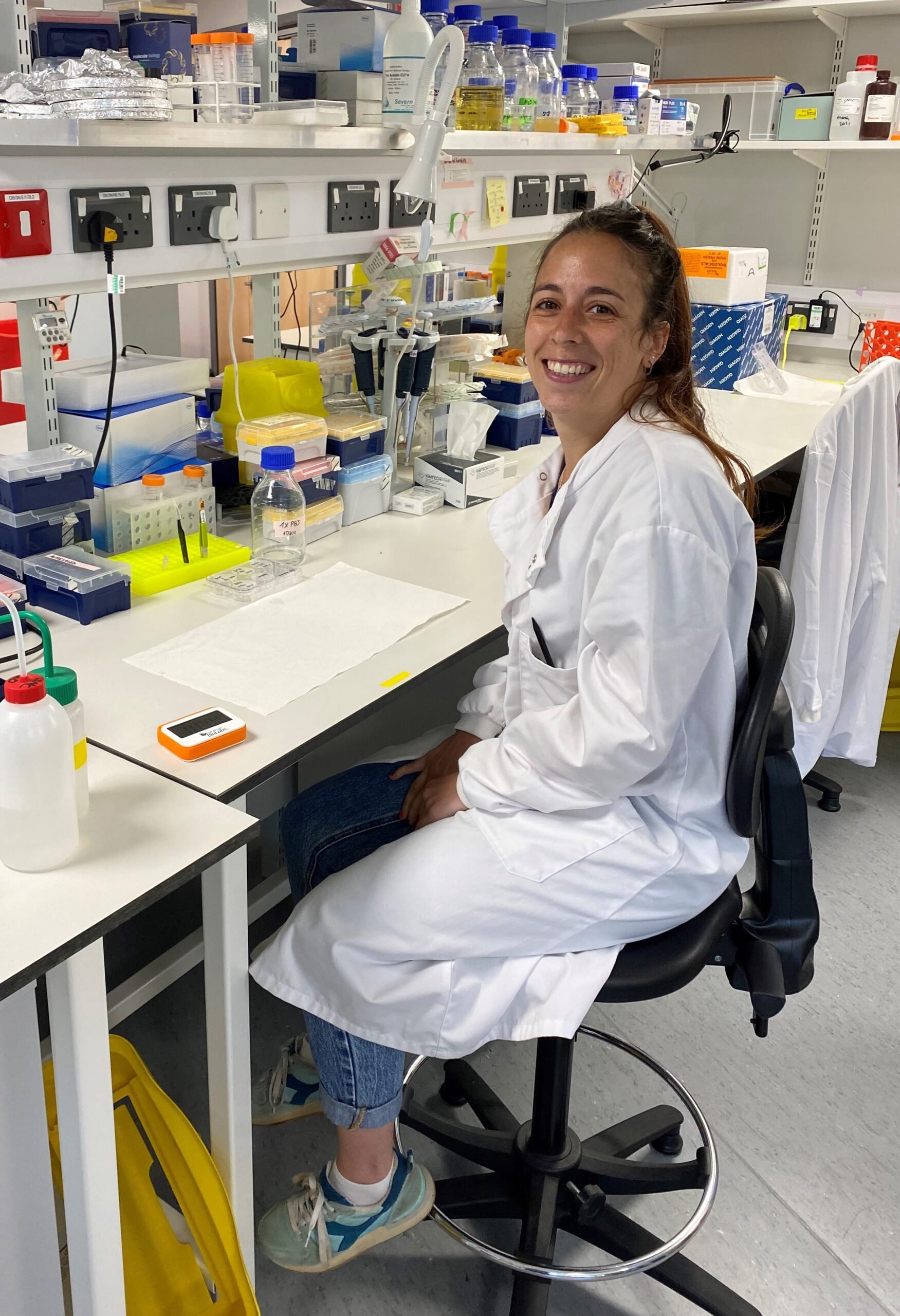 Dr Audrey Lumeau sitting at the laboratory bench in a white lab coat.